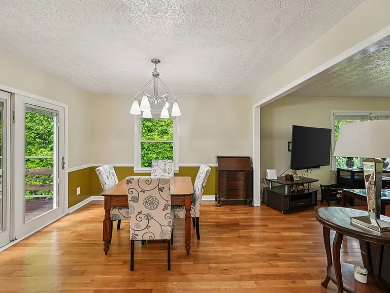 A cheerful dining room wrapped in warm hardwood floors, garden views, and soft natural light, creating a charming setting for meals, conversation, and everyday magic.