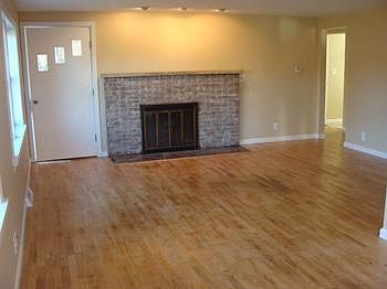 Living room with fresh paint,refinished hardwood floors and wood fireplace.