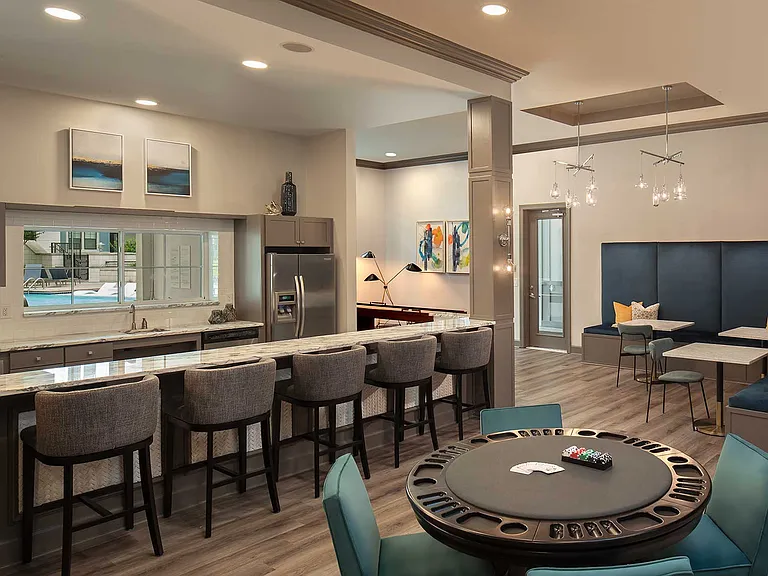 bar area with kitchen, poker table, corner seating with tables, and decor