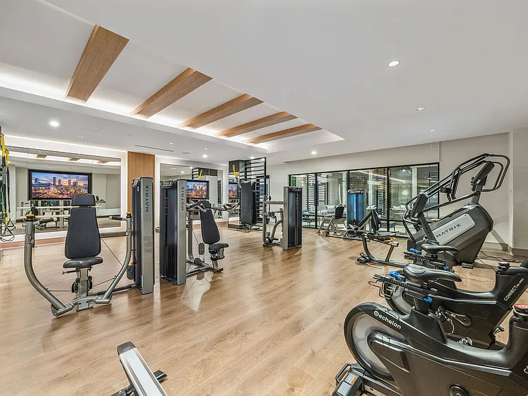 Modern gym facility with state-of-the-art exercise equipment, inviting wooden floors, and sleek design ideal for fitness enthusiasts.