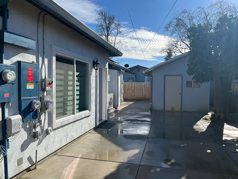 Front of the house with a light next to the main entrance. Two car driveway. Maintenance shed to the right.