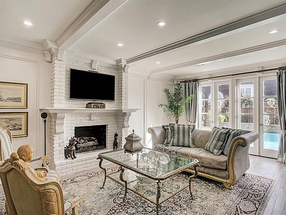 Large den with judges paneling, fireplace with gas logs highlighted by french doors opening to backyard pool.