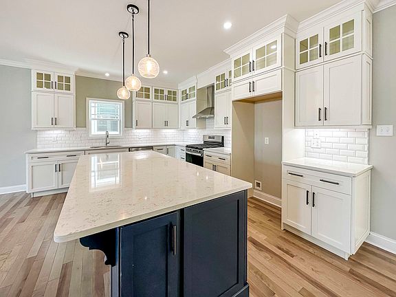 Kitchen with white quartz countertops, white cabinetry, and center island with blue cabinets.