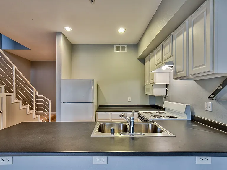 Kitchen featuring white cabinetry, a double basin stainless steel sink, and a white electric range with a range hood