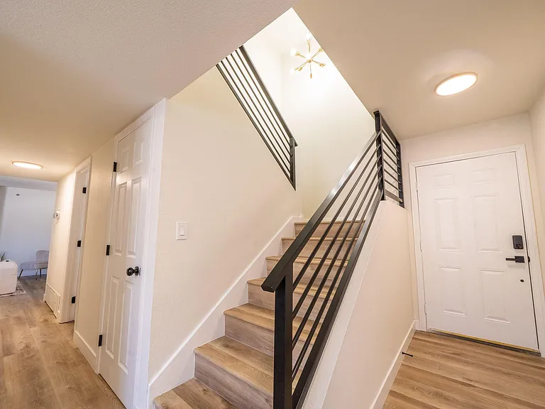 Welcoming entry with wood-look flooring, modern stair railing, and easy access to main living areas and storage.