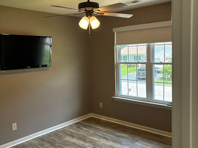 Spare bedroom featuring a ceiling fan, wall mounted TV, and blackout blinds. **All windows facing the front of the house are equipped with blackout blinds to enhance privacy and block vehicle lights at night.