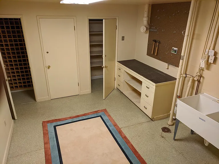 Basement room with sink, workbench and three closets. One has wine storage.