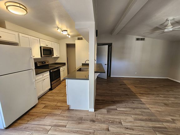 Galley kitchen and family room with door to the backyard on the left. There are ceiling fans throughout the apartment.