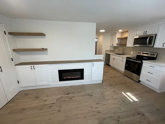 Beautifully finished fireplace with storage cabinets on either side, floating wood shelving and room for a large TV. Wood top waterfall end. Large closet with shelves and hanging rod off the living area