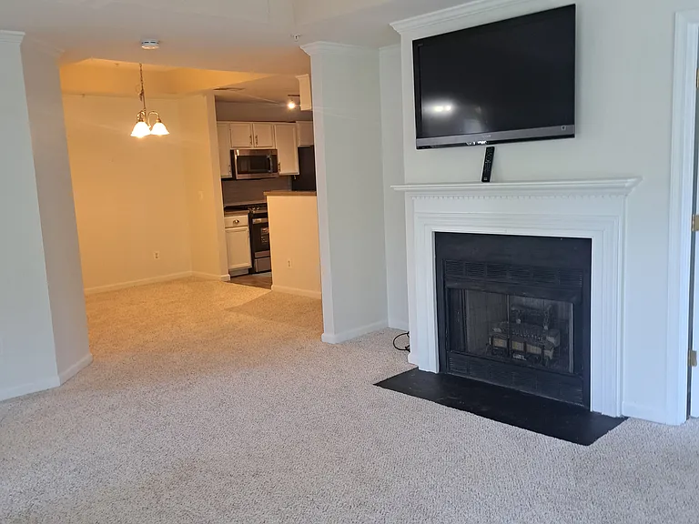 Living room from one angle, showing the dining area in the background near the kitchen. The TV screen comes with the condo.