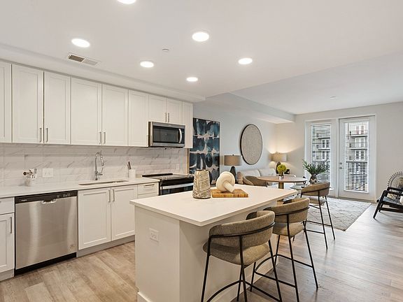 Gourmet Kitchen And Dining Area With White Countertops, Pearl Paneled Cabinets, and Stainless-Steel Appliances