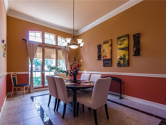 The formal dining room.  The windows look out on the front yard.  Ceramic tile floors with an inlay accent tile.  Chair rail and crown molding.