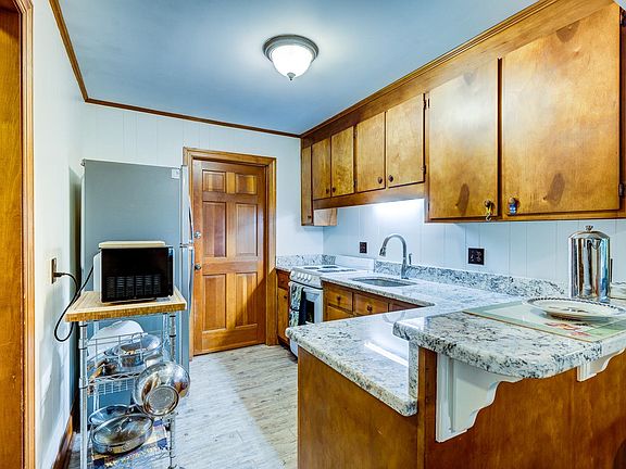 Kitchen with ice-white granite counter tops, GE Hotpoint stove, LG refridgerator and ample cabinet space. Door opens to unfinished basement where dryer & top-load washer located. Cookware not included.