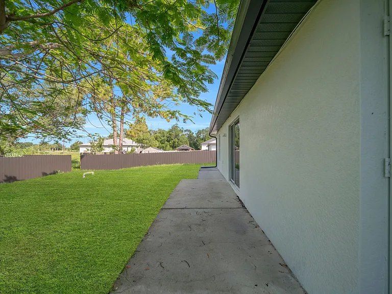 Fenced backyard with a grassy lawn and a concrete patio along the homeideal for relaxing outdoors and easy upkeep.