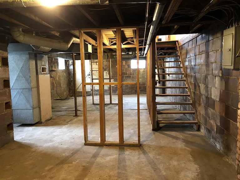 Image of large, unfinished basement with glass block windows and door to back yard.