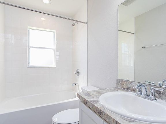 A hall bath serves the secondary bedrooms and guests. Photo showcases a home with similar finishes.