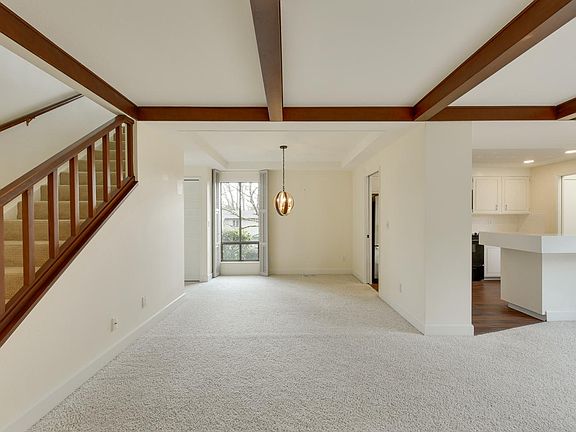 Dining room with decorative ceiling beams and open staircase