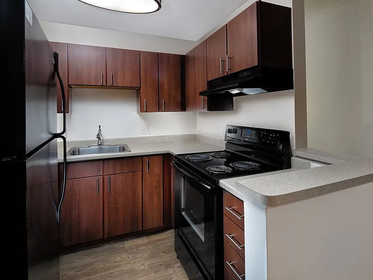 Classic Package II kitchen with cherry cabinetry, light grey laminate countertops, black appliances, and hard surface flooring