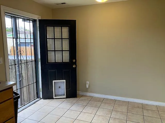 Tile-floored entry area with backyard access with screen door for convenient indoor-outdoor flow.