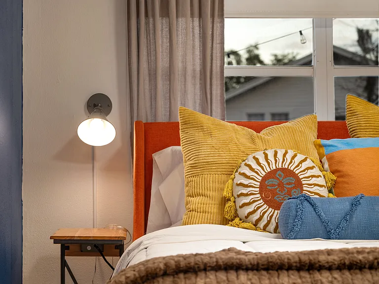 Detail of Queen size bed iand bedside tables and lights in Bedroom three. Bed linens provided include cotton sheets, duvet, extra pillows & blankets. Black out blinds and curtains make this cozy room perfect for sleeping in.