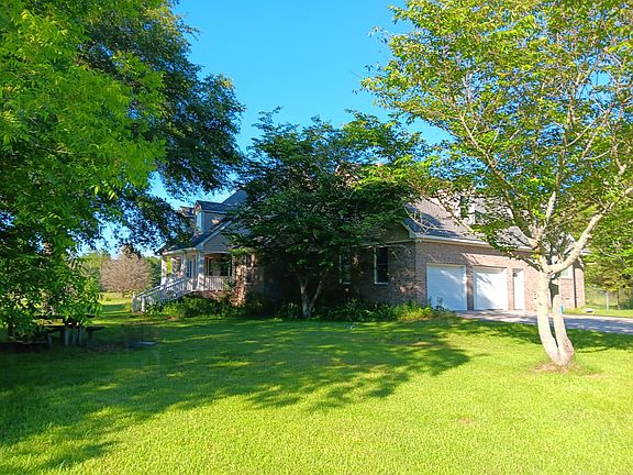 Front view featuring lovely cherry blossom trees and large oak tree. Double car garage and pad.