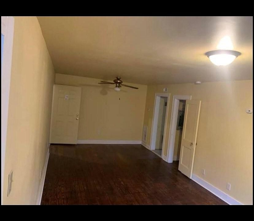 Big open living room, looking into the hallway leading to the bathroom. Second door/opening is to the kitchen.