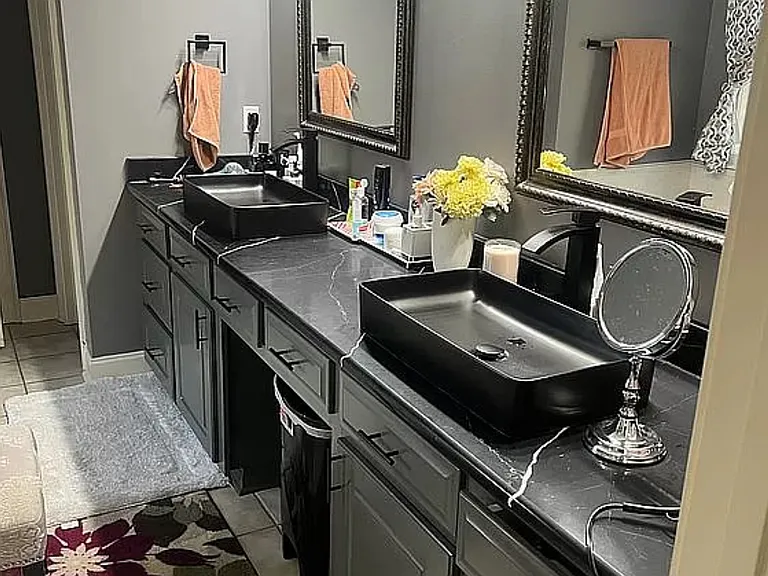 Black quartz with top mount sinks. Jacuzzi and shower stall.