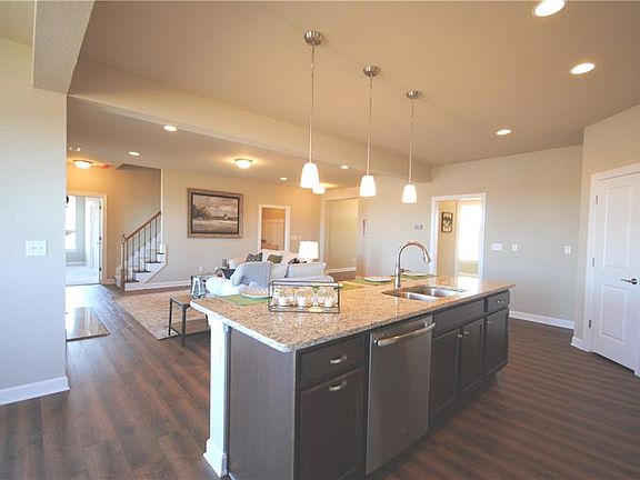 Large kitchen island with overhang for bar stools and pendant lighting.  Dishwasher and trash/recycle pull out in island.
