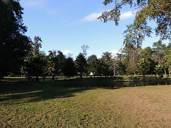 Mature trees and plants surround the pond.