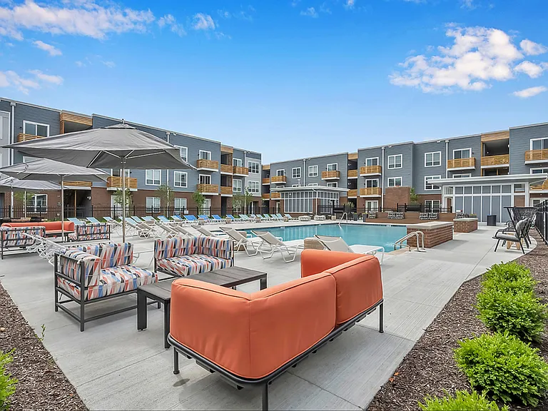 An aerial view of our heated pool with lounge seating, tables, a grilling station, and a community fireplace