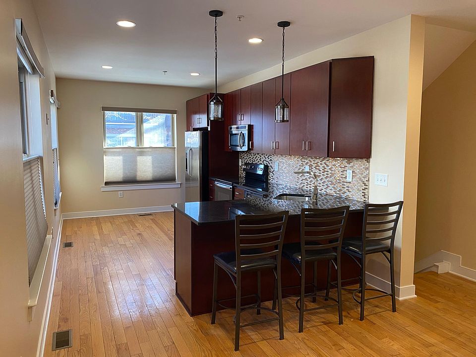First floor open kitchen layout with stainless appliances, hardwood flooring, pull out faucet, metal and glass backsplash (chairs included)