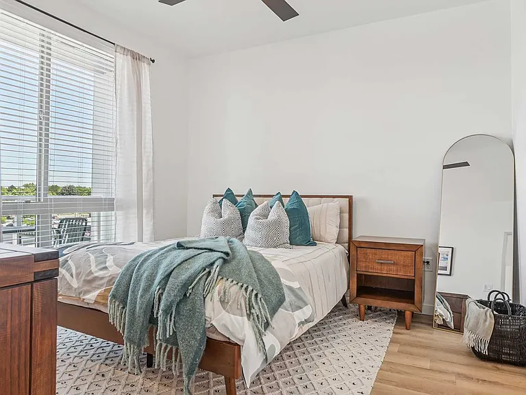 Clean design, warm finishes, and oversized windows create a bright and comfortable bedroom space designed for everyday living.