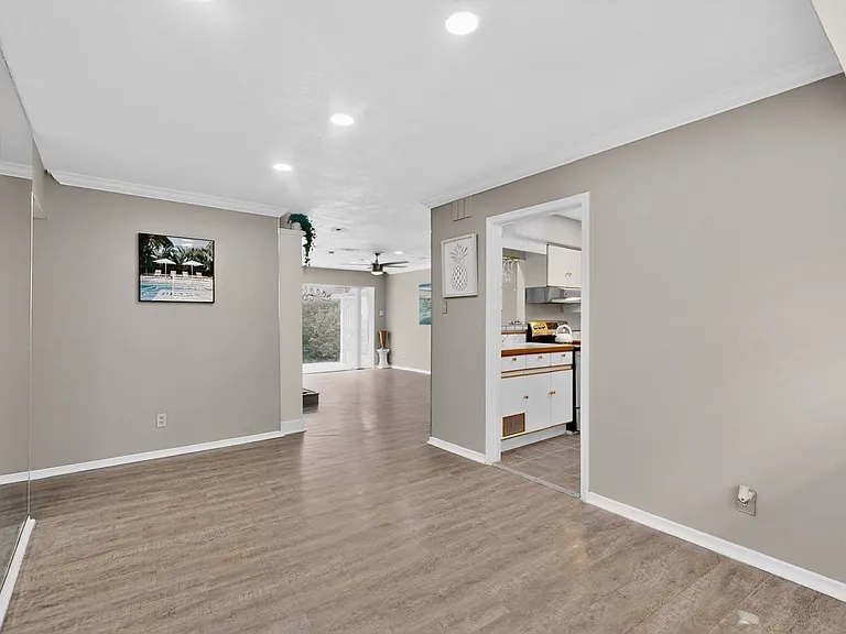 A bright dining area with a wooden floor beside the enclosed kitchen space.