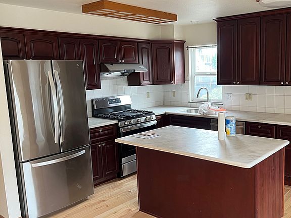 Showing brand new stove and faucet, newer fridge. See also newly re-finished floors.