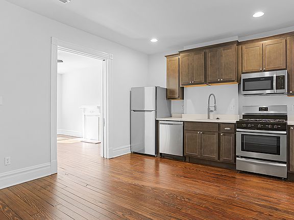 Kitchen looking into the Living Room on the left, salvaged hardwood floors, full stainless steel appliance package with gas oven and microwave, commercial-style kitchen faucet, high-end quartz countertops