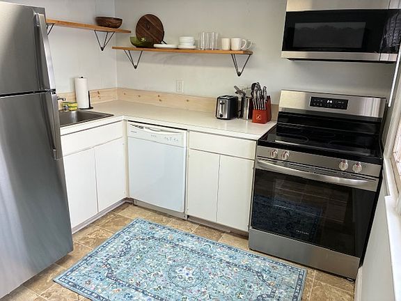 Kitchen with newly installed fridge/freezer, stove, and microwave