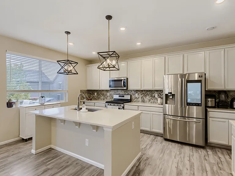 Light, bright and airy with light gray counters, white countertops and a rustic gray-white-washed floors. Samsung fridge with a media hub