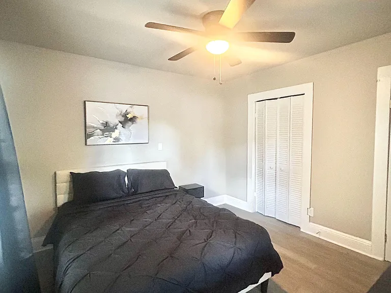 Furnished bedroom with ceiling fan/light, wood-style flooring, and a closet for convenient storage.