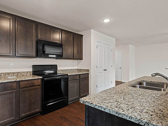The kitchen features granite countertops and stunning wood cabinetry