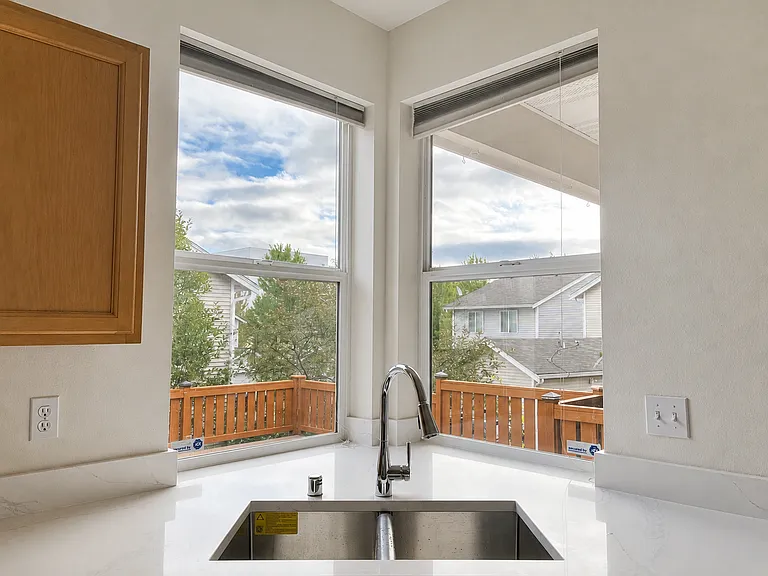 Updated quartz kitchen countertops with views of the backyard featuring a large composite deck with newly installed composite decking