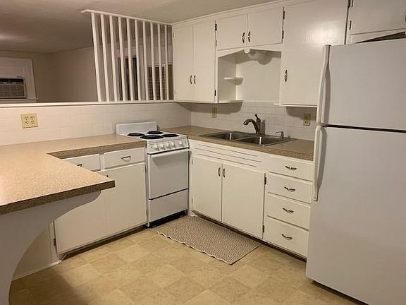 Generous cabinet space; living room view from kitchen; bathroom door is behind wall divider above stove