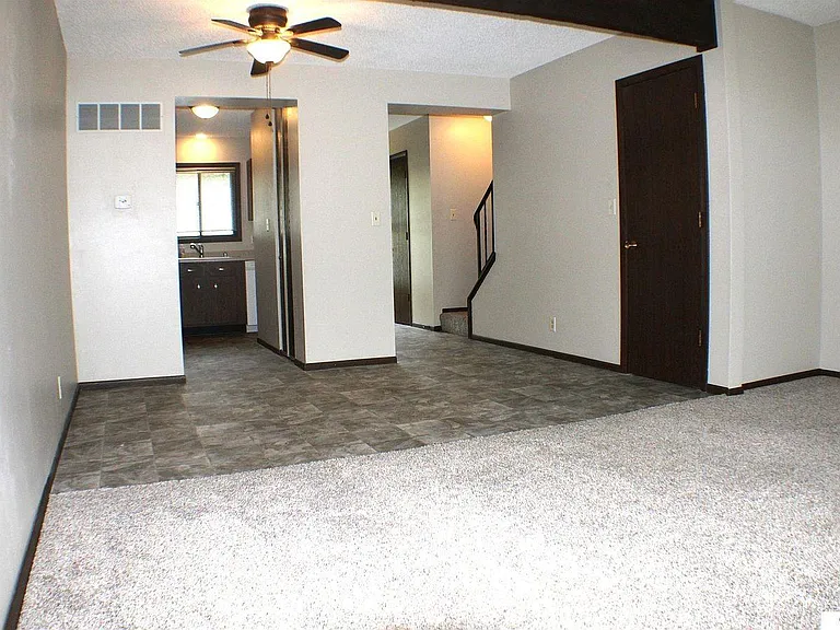 Main level, photo taken from sliding glass door looking into the living room/dining room, with hallway and kitchen. Half bath is tucked in the hallway before the stairs.