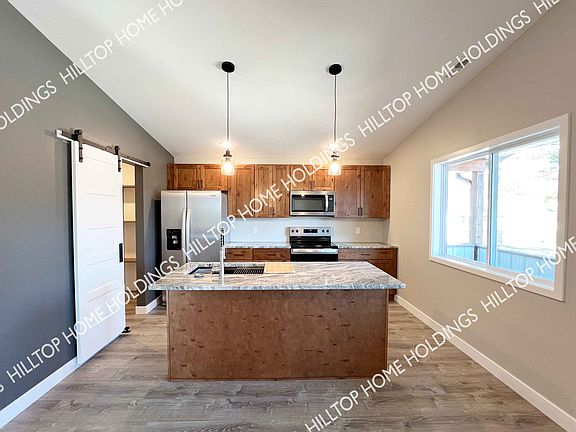 Kitchen is equipped with a refrigerator, range, dishwasher, and microwave. This unit is still under construction. Photo of neighboring unit with similar finishes.