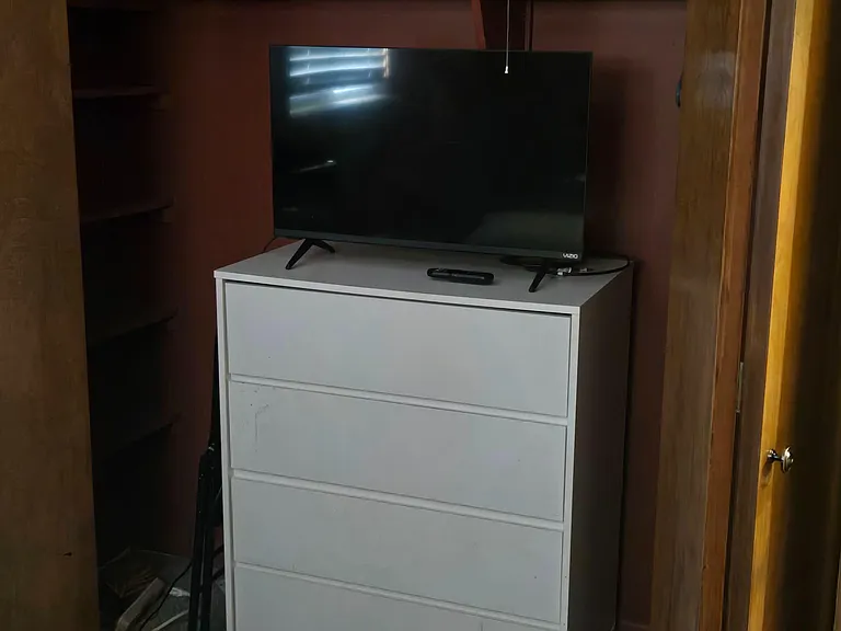 Built-in closet nook offers convenient storage with shelving and space for a dresser and TV setup.
