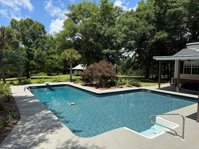 L-Shaped pool with shaded patio. Comes with a net for playing badminton or volleyball.