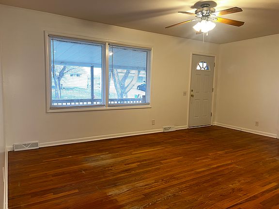 Large living room with hardwood floors and freshly painted interior & ceiling fan.