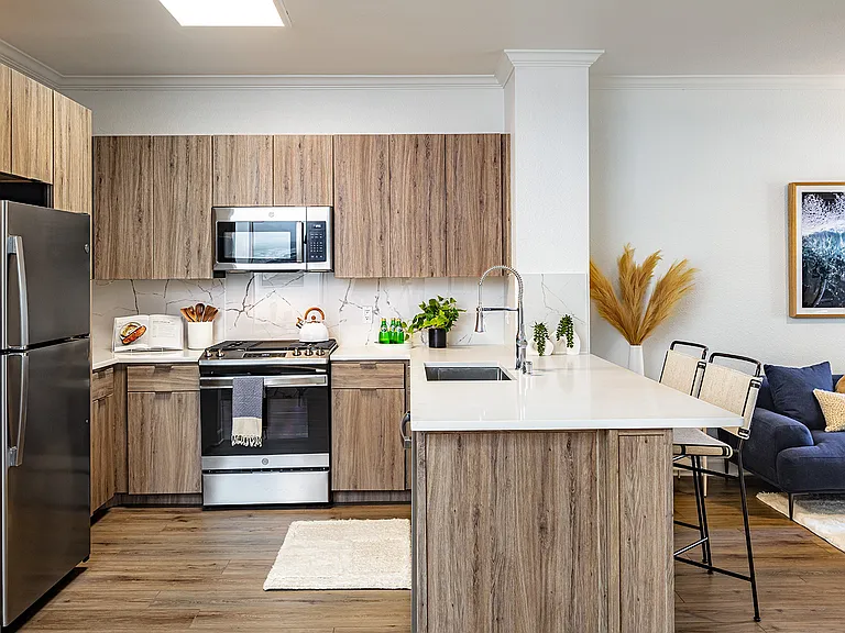 A kitchen with wood-look cabinets, stainless steel appliances, and a breakfast bar with seating.