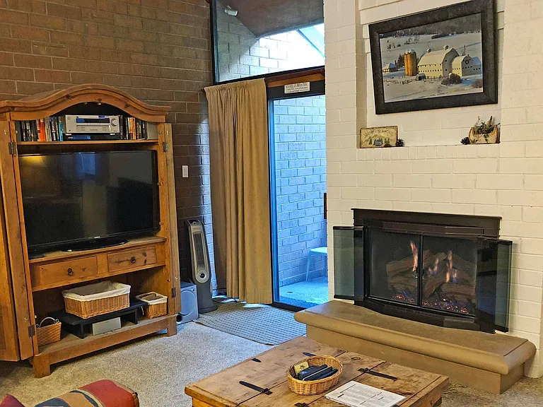 The living room has a large 54" smart TV, DVD, and stereo system. The sliding doors lead to a patio and the golf /x-country courses.