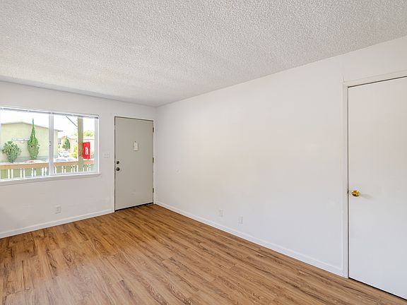 Light-filled living room with wood-style flooring, a large window, and a simple layout ready for your personal touch.