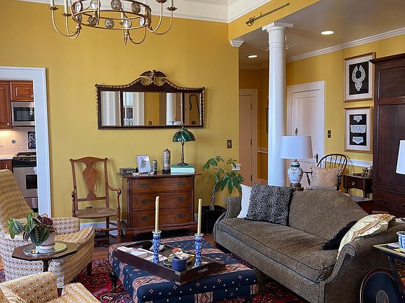 Living room looking toward front door at far right, one of two kitchen entries at left - wonderful high ceilings and bright natural light; interior shutters on all windows are great for darkening if you prefer.